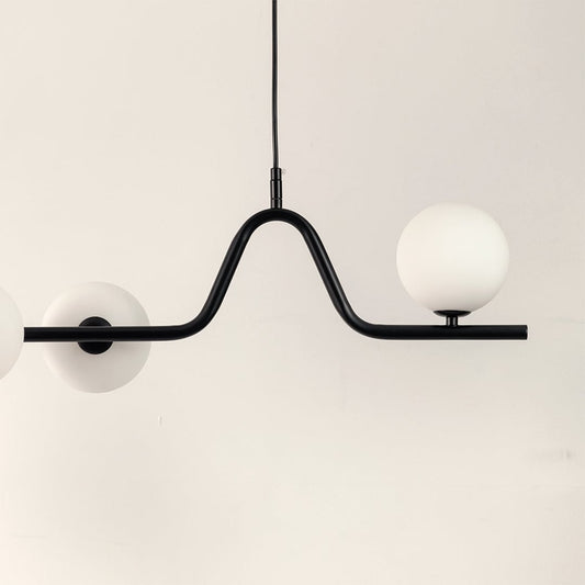 Closeup of black metal chandelier showing curved frame frosted globes and refined contemporary craftsmanship.