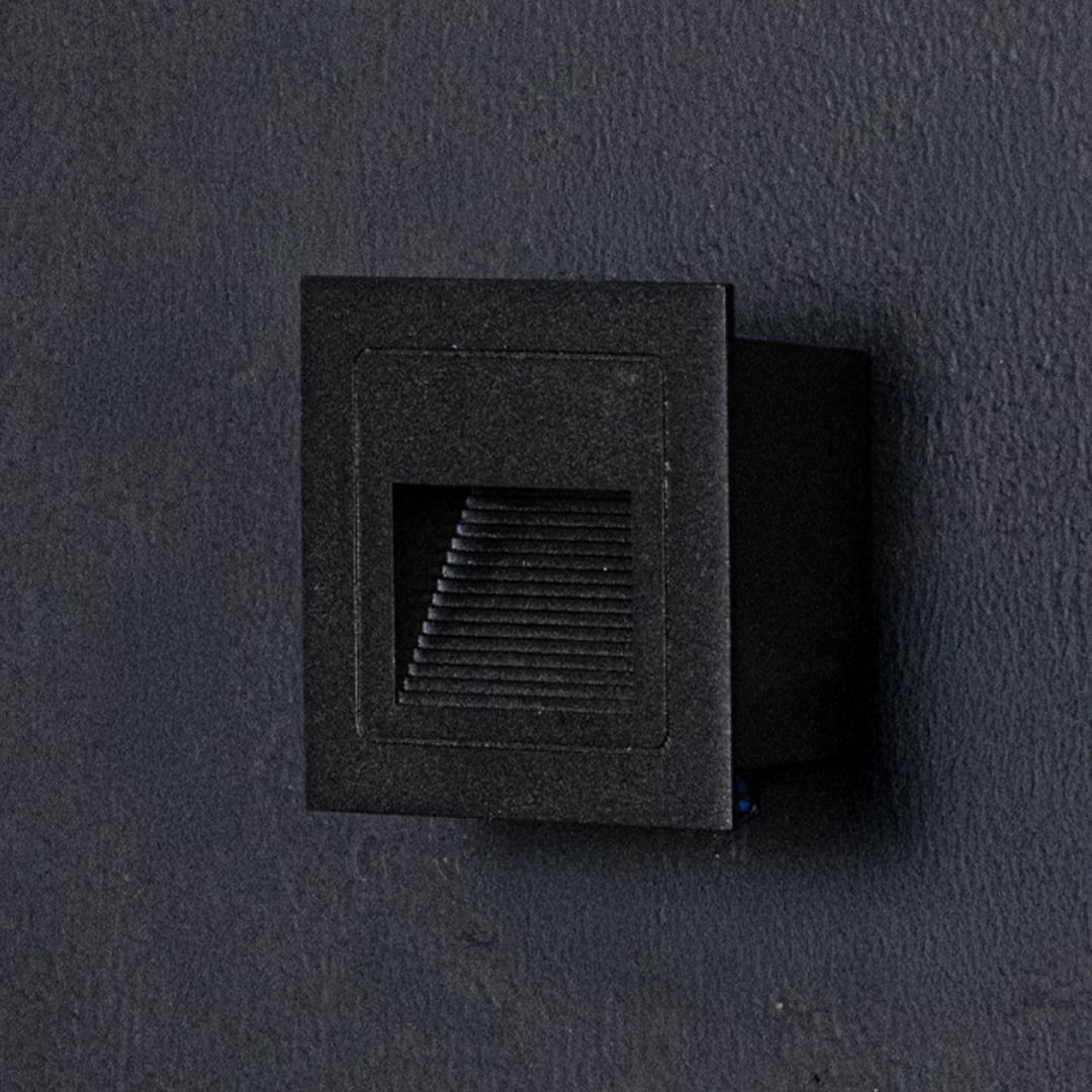 Minimal black recessed wall step light displayed off on dark background highlighting sleek modern design.